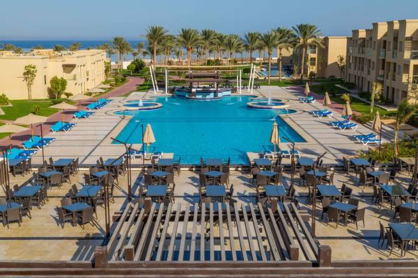 Rixos Premium Seagate Hotel Außenbereich mit Pool, Sonnenliegen und Tischen.