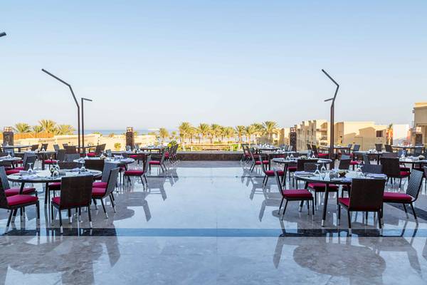 Außenbereich des Rixos Premium Seagate Hotels mit runden Tischen und Stühlen, Meer im Hintergrund.
