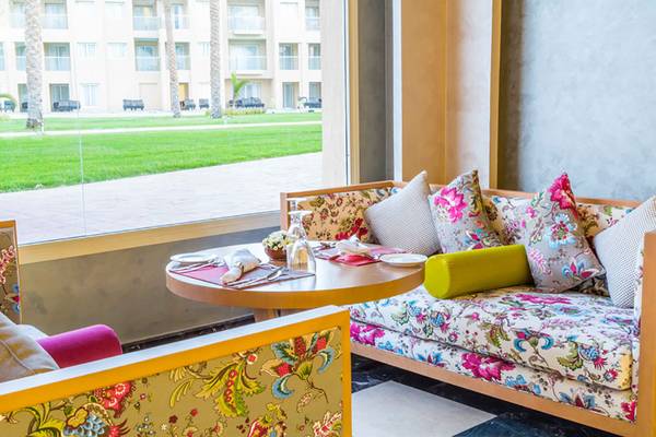 Lounge-Bereich des Rixos Premium Seagate Hotels mit blumigen Sofas und Tisch, Blick auf Rasen.