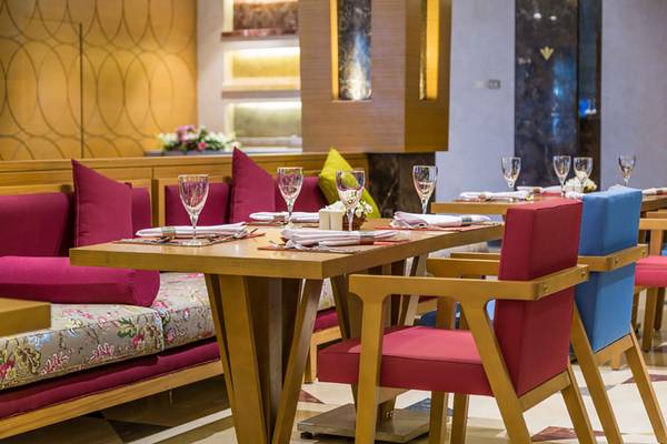 Restauranttisch im Rixos Premium Seagate mit rot und blau gepolsterten Stühlen.