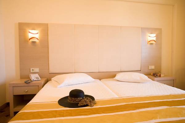 Doppelzimmer im Kresten Palace Hotel mit zwei Betten, weißen Kissen und einem schwarzen Hut auf dem Bett.