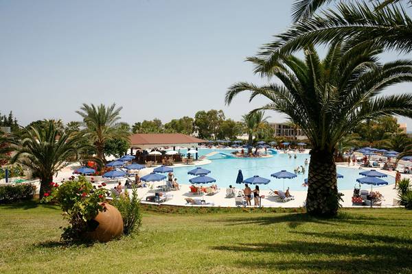 Außenbereich des Kresten Palace Hotels mit großem Pool und vielen Liegestühlen und Sonnenschirmen.