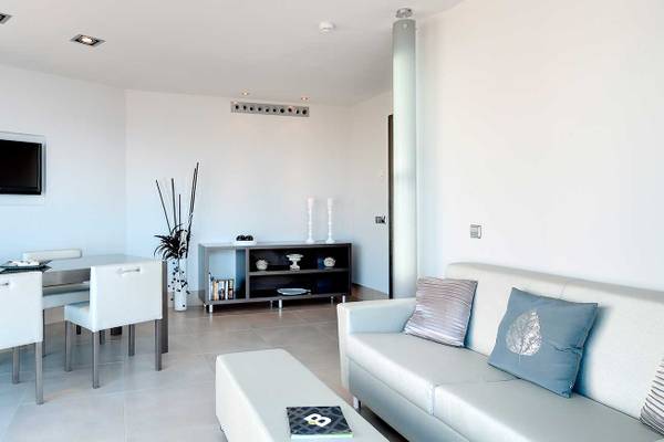Wohnbereich des Barcelo Illetas Albatros Hotel mit weißem Esstisch, Stühlen und Sofa.