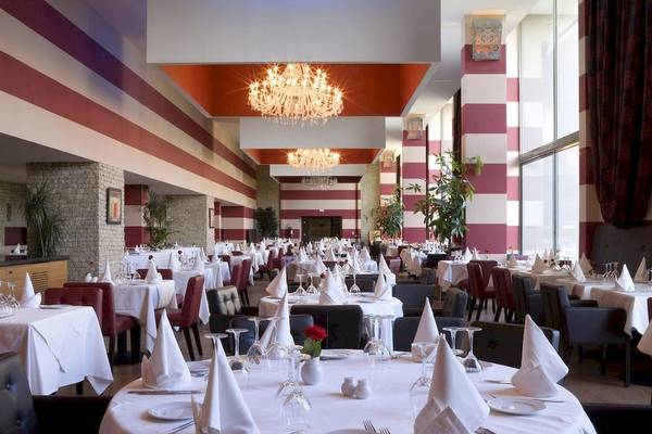 Das elegante Restaurant des Royal Atlas & Spa Hotels mit gemusterten Wänden und Tischdekoration.