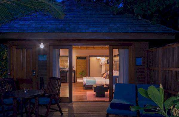 Nachtansicht eines Bungalows im Veligandu Island Resort & Spa mit Außenbereich, Möbeln und Beleuchtung.