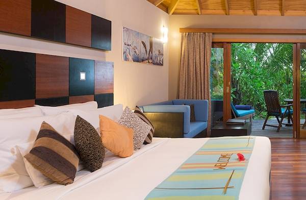 Schlafzimmer im Veligandu Island Resort & Spa mit Blick auf einen Garten durch Glastüren.