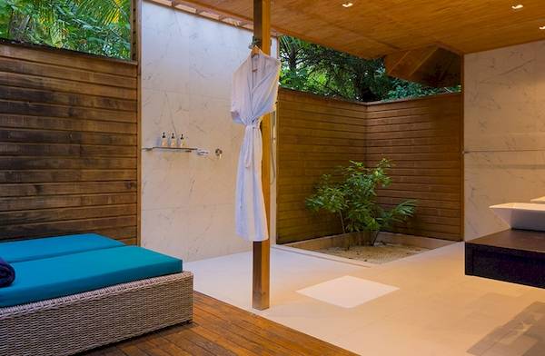 Ein Badezimmer im Veligandu Island Resort & Spa mit einer Dusche, Liege und Pflanzen.