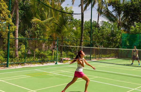 Tennisplatz im Veligandu Island Resort & Spa mit einer Frau und einem Mann, die spielen.