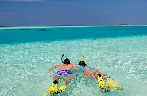Zwei Personen schnorcheln im kristallklaren Wasser beim Veligandu Island Resort & Spa.