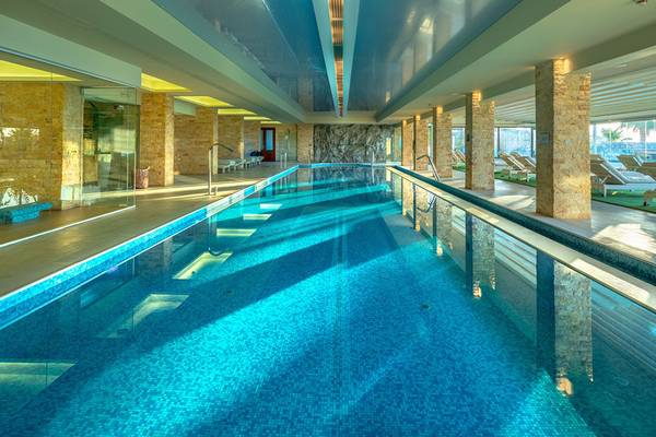 Innenpool des Ikaros Beach Luxury Resort & Spa mit blauem Wasser und Säulen