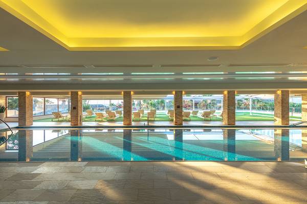 Innenpool des Ikaros Beach Luxury Resort & Spa mit Lounge-Bereich und Pflanzen