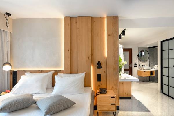 Zimmer im Ikaros Beach Luxury Resort & Spa mit Bett, Kissen, Holzkopfteil und Badezimmer