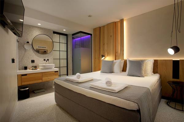 Innenansicht eines Zimmers im Ikaros Beach Luxury Resort & Spa mit Bett, Holzwänden und Badezimmer.