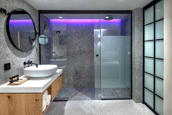 Badezimmer im Ikaros Beach Luxury Resort & Spa mit runden Spiegel und Waschbecken