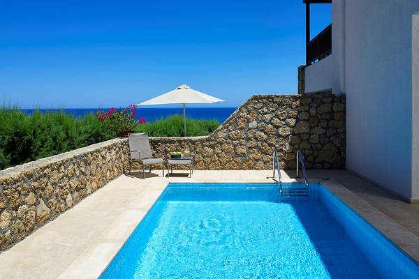 Außenpool des Ikaros Beach Luxury Resort & Spa mit Blick auf das Meer.