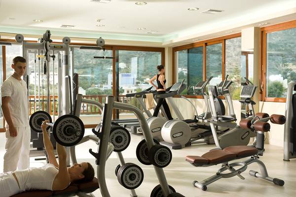 Fitnessbereich des Ikaros Beach Luxury Resort & Spa mit Geräten und Fenstern.