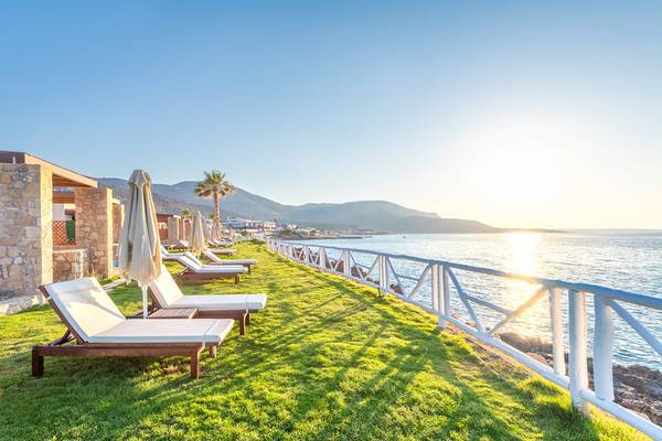 Ikaros Beach Luxus Resort & Spa Terrasse mit Liegen und Meerblick bei Sonnenuntergang