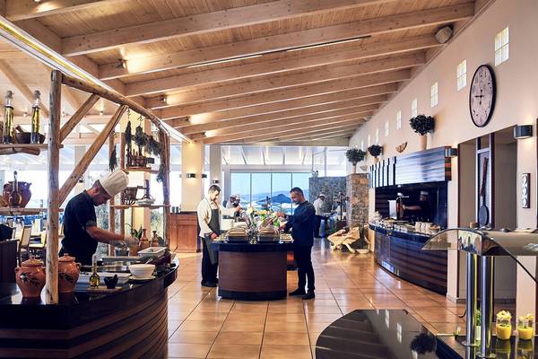 Restaurant im Ikaros Beach Luxury Resort & Spa mit Personen bei der Essenszubereitung und Blick auf das Meer.
