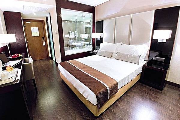 Ein modernes Hotelzimmer im Turim AV Liberdade Hotel mit einem Doppelbett, Schreibtisch, Laptop, und Badezimmerspiegel.