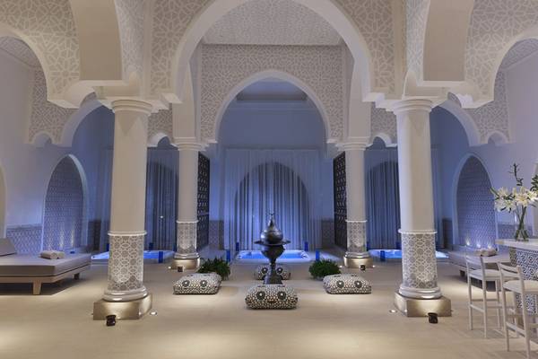 Innenbereich des Steigenberger Alcazar mit weißen Säulen, geometrischen Mustern, Loungebereich und zentralem Wasserbrunnen.