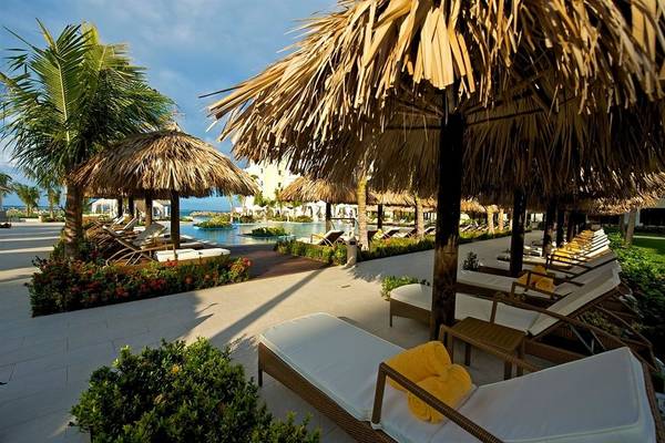 Außenbereich des Iberostar Grand Rose Hall Hotels mit Lounge-Stühlen und Sonnenschirmen.