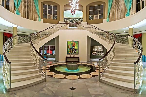 Foyer des Iberostar Grand Rose Hall Hotels mit einer doppelgeschossigen Treppe und einem zentralen Brunnen.