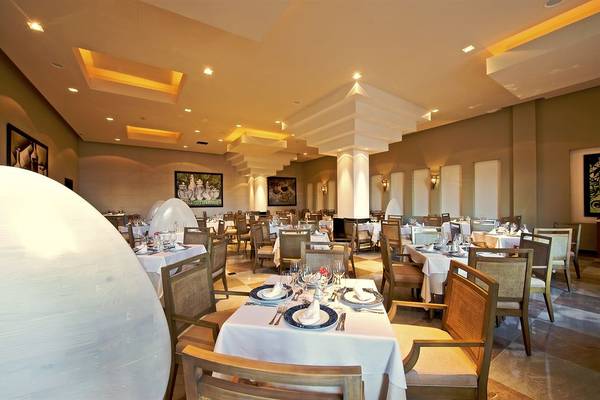 Innenansicht des Restaurants im Iberostar Grand Rose Hall Hotel mit gedeckten Tischen und Stühlen.