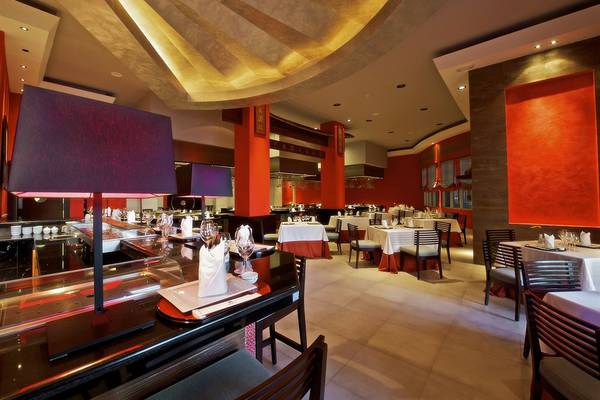 Innenansicht des Restaurants im Iberostar Grand Rose Hall Hotel mit roten Wänden und weißen Tischen.
