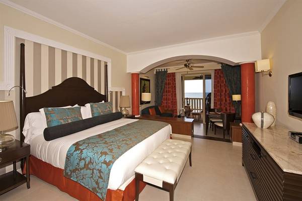 Schlafzimmer im Iberostar Grand Rose Hall Hotel mit Doppelbett, Balkon und Meerblick.