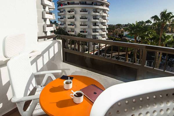 Blick vom Balkon des Servatur Waikiki Hotels auf ein rundes Gebäude und Palmen.