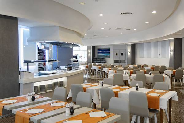 Servatur Waikiki Hotel Restaurant mit mehreren Tischen und Stühlen, eine Küche im Hintergrund.