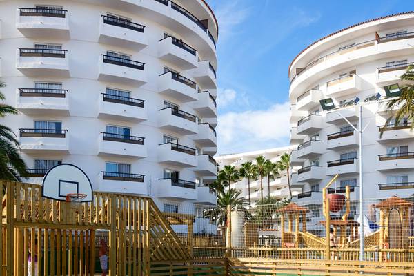 Außenbereich des Servatur Waikiki Hotels mit Gebäuden, Spielplatz und Basketballkorb