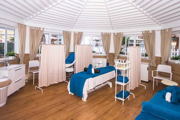 Behandlungsraum im Servatur Waikiki Hotel mit Massageliegen und blauen Laken.