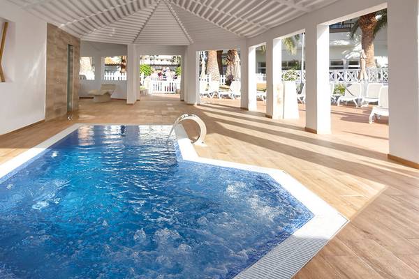 Innenpool des Servatur Waikiki Hotels mit hellen Holzböden und weißen Säulen.