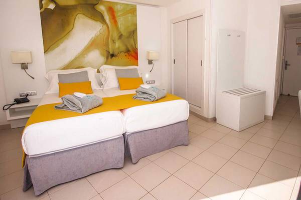 Innenansicht eines Doppelzimmers im Servatur Waikiki Hotel mit zwei Betten und modernen Möbeln.