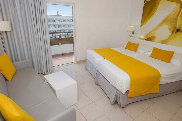 Zimmer im Servatur Waikiki Hotel mit Sofa und Balkonzugang.