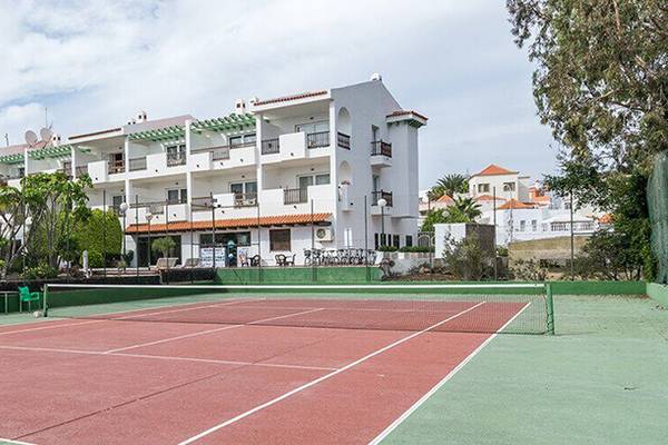 Tennisplatz vor dem Hotel Bluesea Callao Garden mit weißen Gebäuden und Bäumen im Hintergrund.