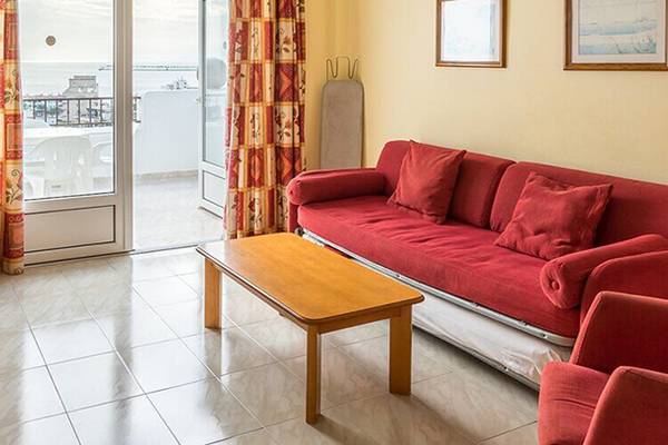 Wohnzimmer im Bluesea Callao Garden Hotel mit rotem Sofa, Couchtisch und Fernseher.