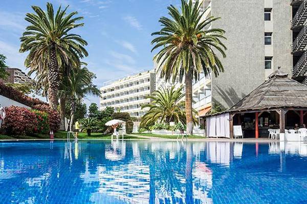 Ein Swimmingpool des Bluesea Callao Garden Hotels mit Palmen und Gebäuden im Hintergrund.