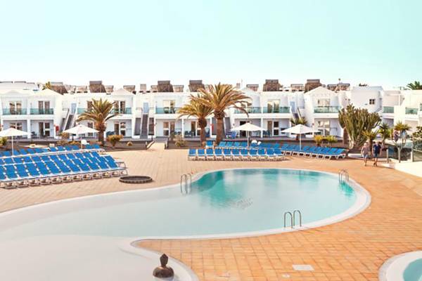 Außenpool mit Sonnenliegen und Sonnenschirmen im BLUESEA Callao Garden Hotel.