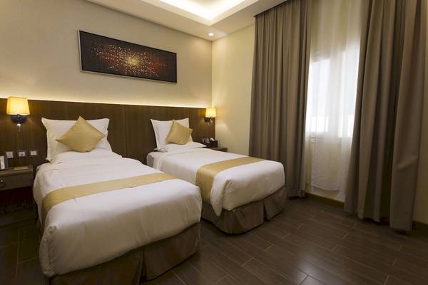 Doppelzimmer im Belad Bont Resort mit zwei Betten, goldenen Kissen und Wanddekoration.
