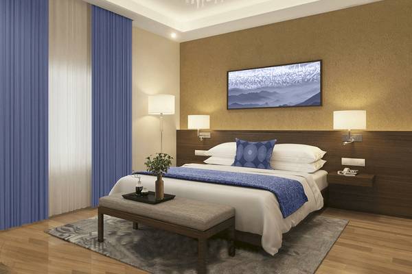 Schlafzimmer im Belad Bont Resort mit einem großen Bett, blauen Vorhängen und einem Gemälde an der Wand.