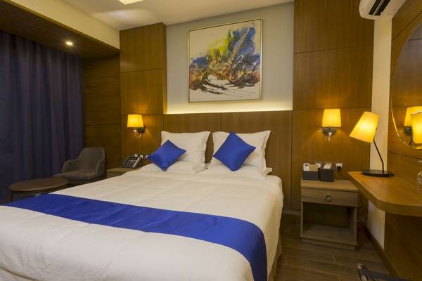 Hotelzimmer im Belad Bont Resort mit einem Doppelbett, blauen Kissen und dekorativen Wandleuchten.
