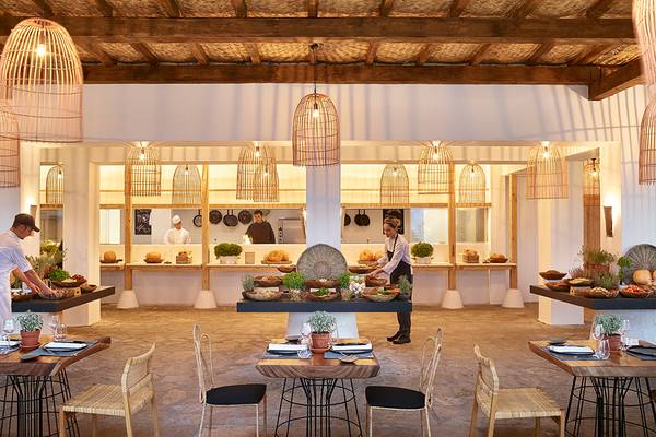 Innenansicht des Restaurants im Grecotel Casa Marron mit Köchen, die Gerichte zubereiten, und gedeckten Tischen.