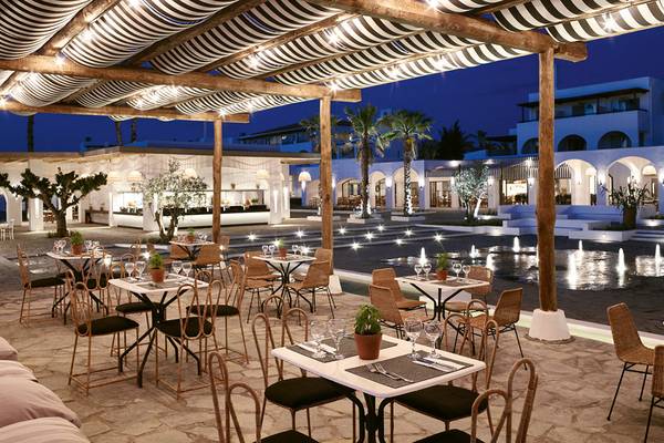 Außenbereich des Grecotel Casa Marron Hotels mit beleuchteten Tischen und Stühlen bei Nacht.