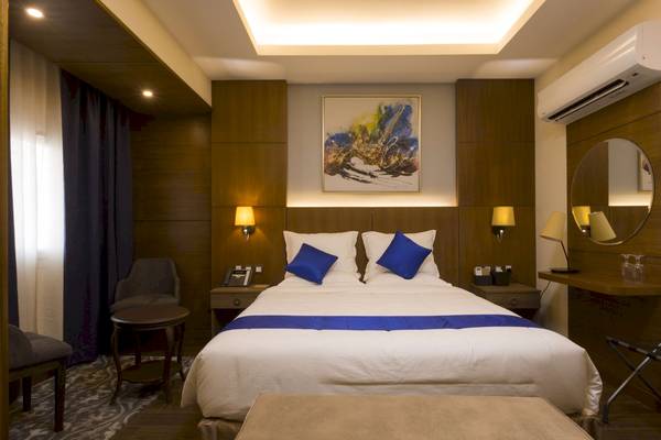 Ein elegantes Hotelzimmer mit einem großen Bett, zwei blauen Kissen und einer modernen Einrichtung.