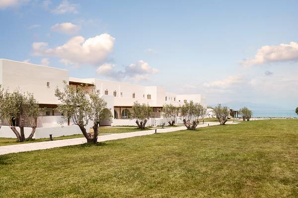 Außenansicht des Grecotel Casa Marron Hotels mit weißen Gebäuden und einem grünen Rasen.