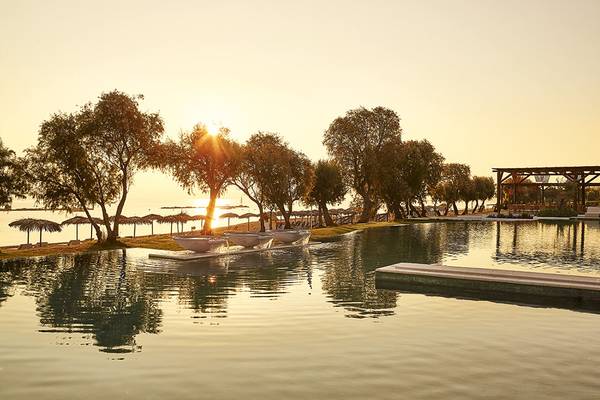 Sonnenuntergang am Pool des Grecotel Casa Marron mit Bäumen und Meer im Hintergrund