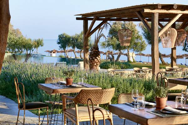 Außenbereich des Grecotel Casa Marron Hotels mit Tischen, Stühlen und Pflanzen, Blick auf den See.