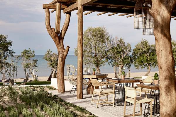 Restaurantsitzplätze am Strand in Griechenland mit Blick auf das Meer und Bäume.